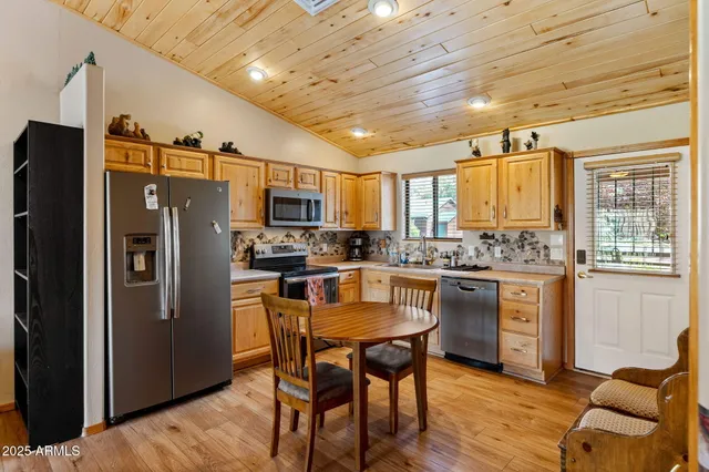 a kitchen with granite countertop a refrigerator a stove a sink dishwasher a dining table and chairs with wooden floor