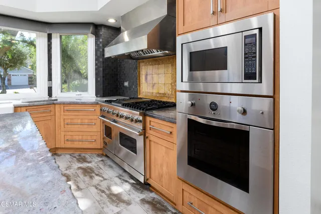 an empty room with wooden floor chandelier and windows