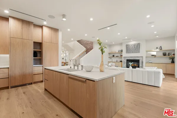 a large kitchen with kitchen island a large counter space a sink a stove and a window