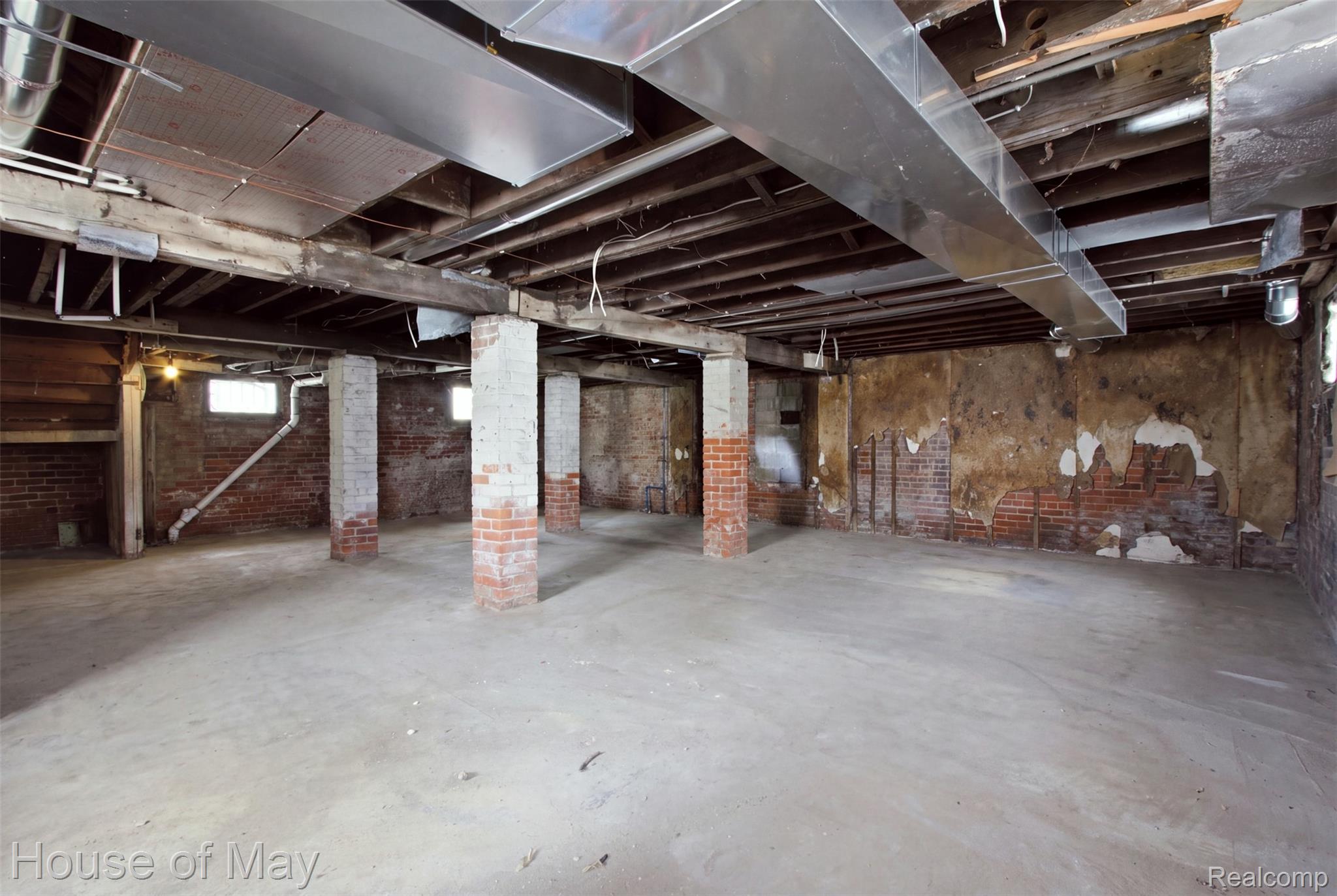 676 Atkinson Street Detroit, MI 48202 - Photo 16 of 17 Unfinished basement with exposed brick walls, concrete flooring, support columns, and exposed ceiling beams