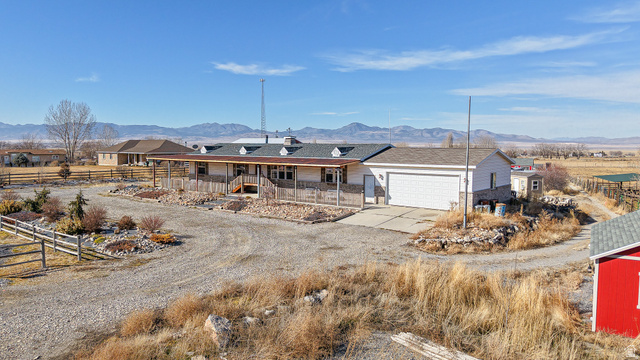 718 South State Street Genola, UT 84655 - Photo 8 of 19 Ranch-style residence featuring a covered front porch with stone accents, an attached two-car garage, and a gravel driveway