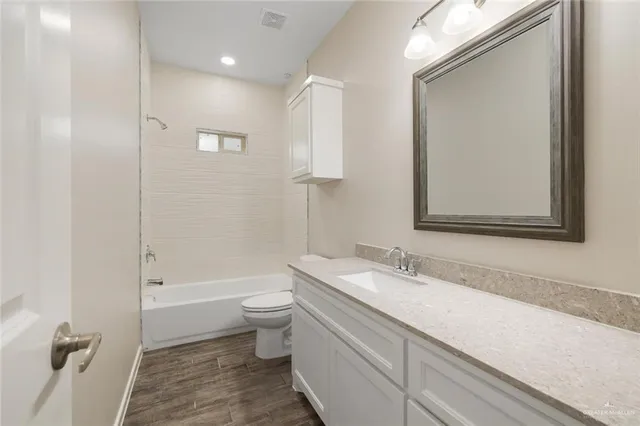 a bathroom with a granite countertop sink a toilet and shower