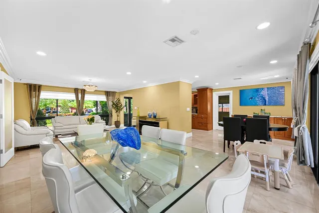 a living room with furniture and a dining table with projector the kitchen