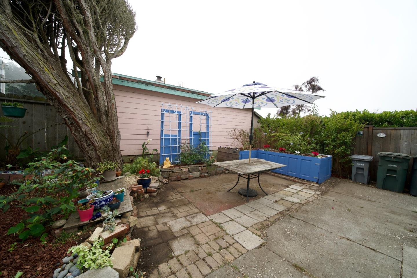 390 Pacific Avenue Pacifica, CA 94044 - Photo 23 of 24 a view of a patio with table and chairs potted plants and large tree