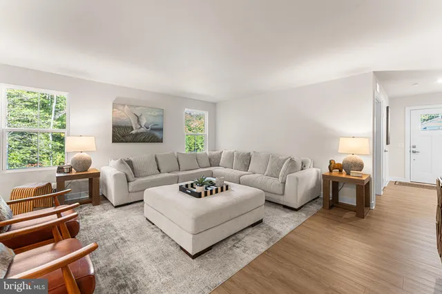 a living room with furniture wooden floor and a large window