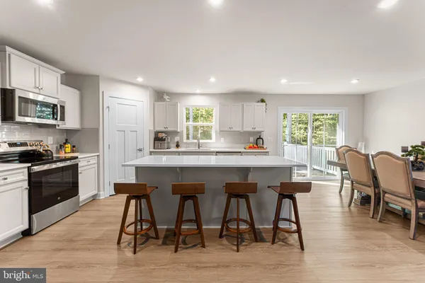 a kitchen with stainless steel appliances granite countertop a table chairs sink refrigerator and cabinets