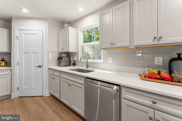 a kitchen with white cabinets and sink