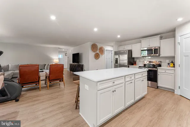 a large white kitchen with stainless steel appliances granite countertop a stove and a refrigerator