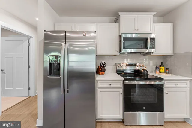 a kitchen with stainless steel appliances granite countertop a refrigerator a stove and a sink