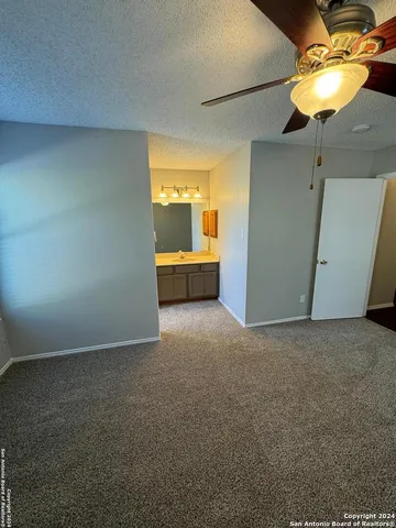 a view of an empty room with a chandelier fan