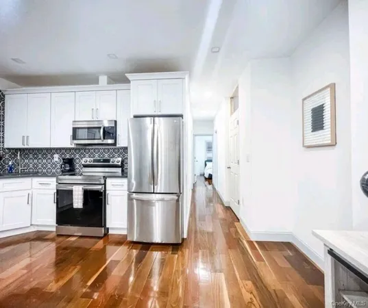 a kitchen with a refrigerator a stove top oven and white cabinets