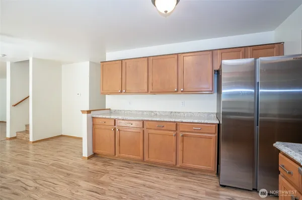 a kitchen with granite countertop a refrigerator and cabinets