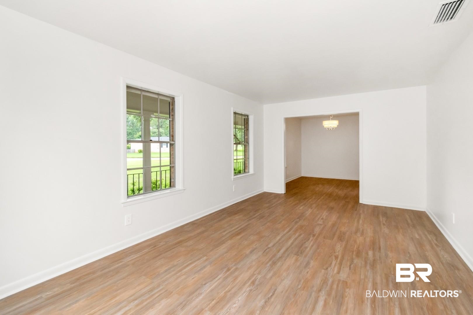 5217 Perin Road Mobile, AL 36693 - Photo 4 of 45 Spacious living area featuring wood-finish flooring, white walls, and bright window treatments