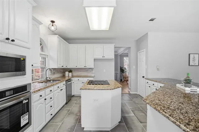 a kitchen with granite countertop white cabinets and white appliances