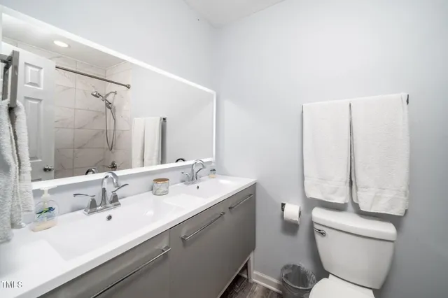 a bathroom with a double vanity sink toilet and a mirror