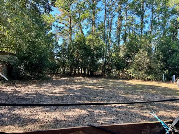 a tall yellow house with trees in the background