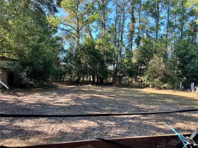a tall yellow house with trees in the background