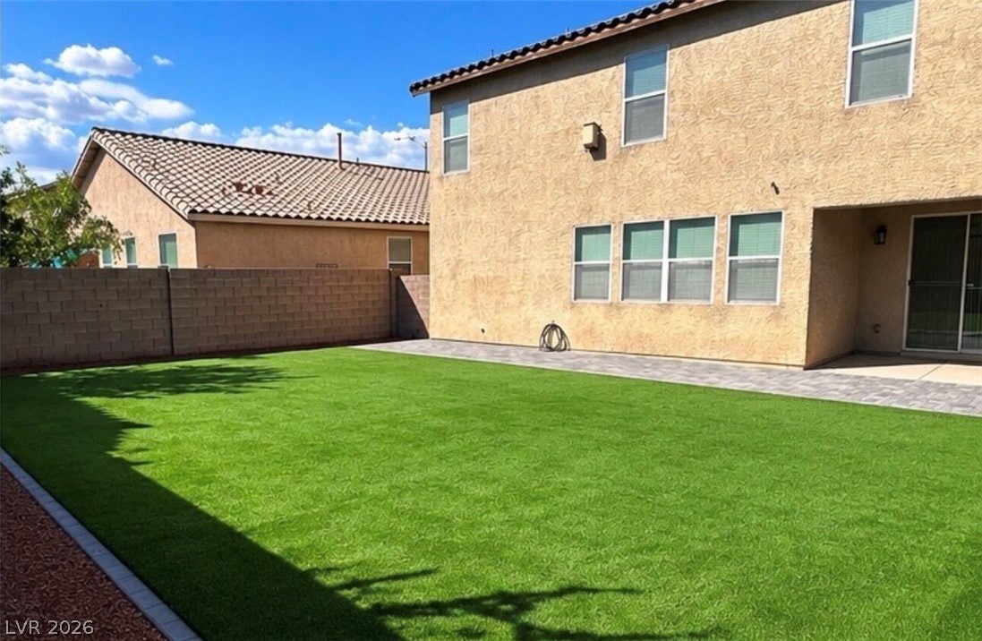 9639 West Post Road Las Vegas, NV 89148 - Photo 27 of 30 An expansive green lawn sits beside a paved patio area along the back stucco wall.