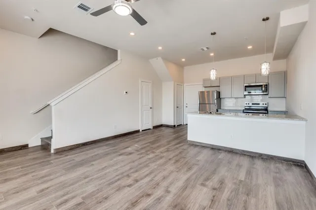 a large kitchen with stainless steel appliances refrigerator a stove top oven and wooden floor