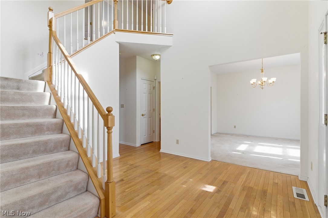 25684 Tryon Road Bedford, OH 44146 - Photo 2 of 19 Staircase with hanging lights, hardwood / wood-style flooring, carpet floors, and a high ceiling