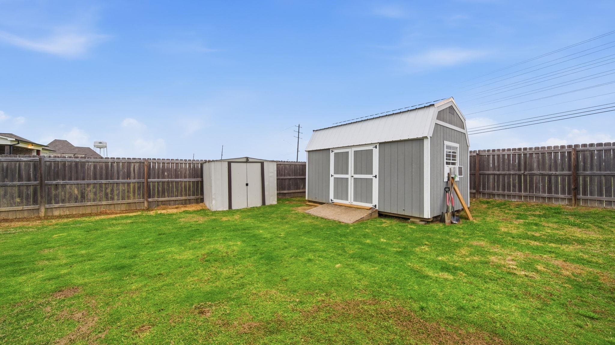 70 Trinity Cove Atoka, TN 38004 - Photo 22 of 25 Expansive green lawn featuring a large storage shed with a gambrel roof and a smaller utility shed