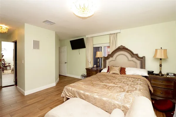 a bedroom with a bed and a dresser with wooden floor