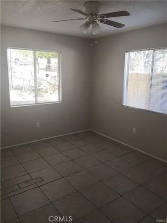 an empty room with windows and fan
