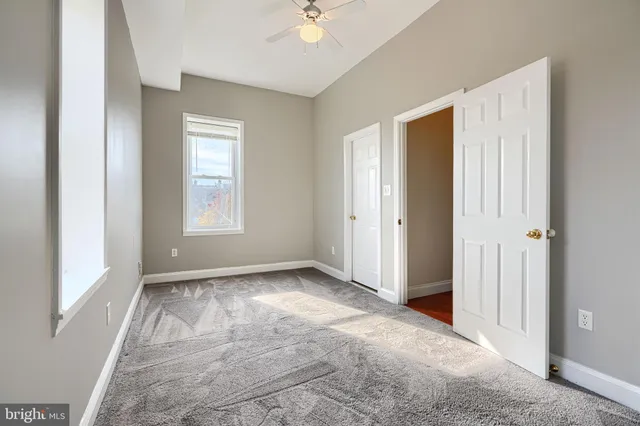 an empty room with windows and a ceiling fan