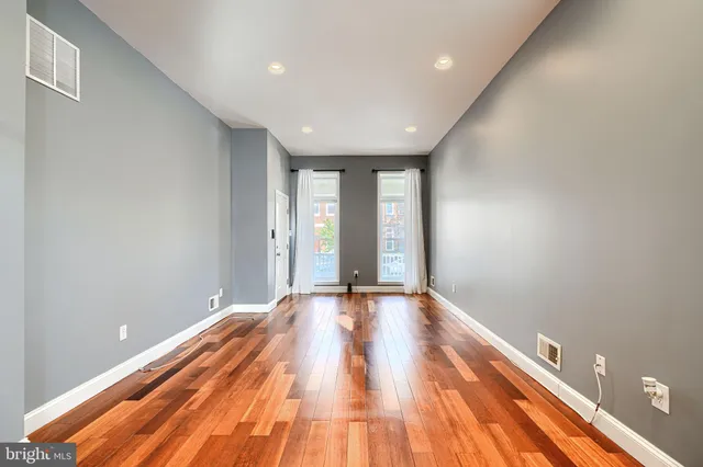 a view of an empty room with wooden floor and window