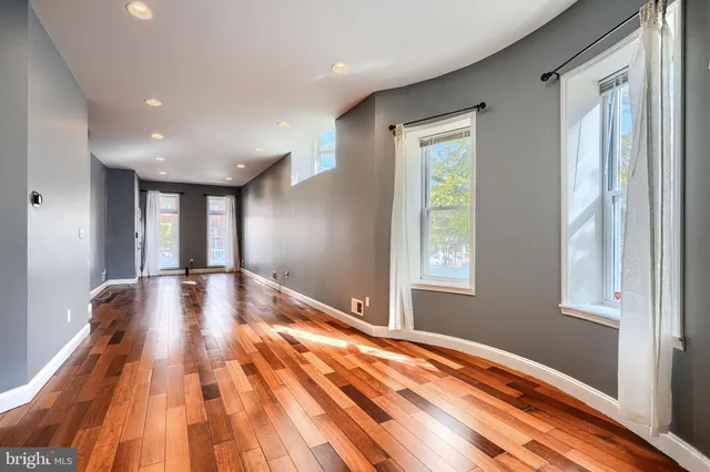 a view of an empty room with window and wooden floor