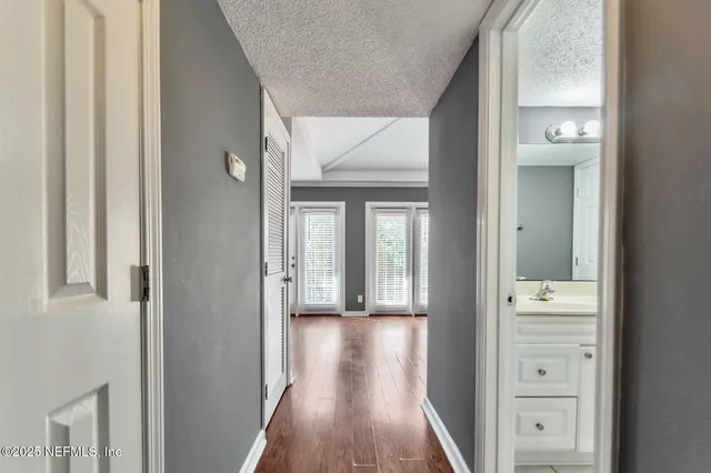 a view of a hallway with wooden floor windows and a bathroom