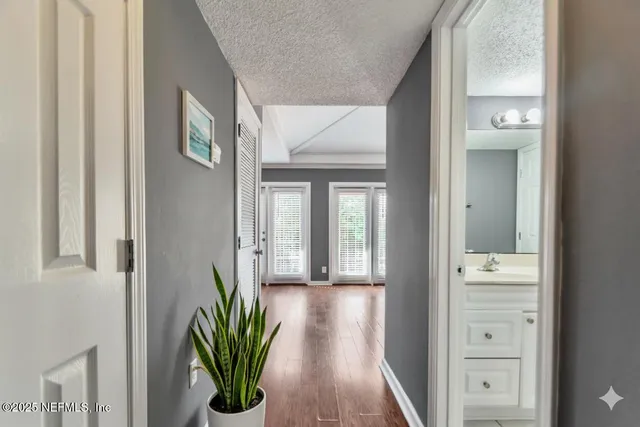 a view of a hallway with wooden floor and a dining room