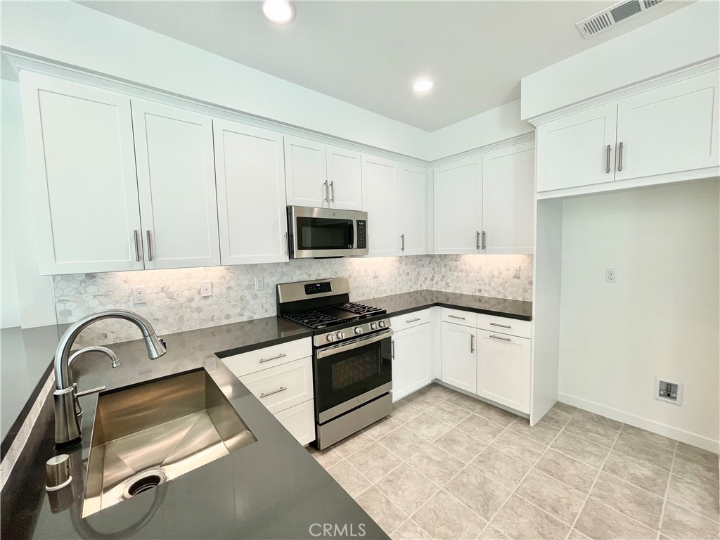 39396 Corvina Lane Temecula, CA 92591 - Photo 11 of 63 a kitchen with granite countertop a sink stainless steel appliances and white cabinets
