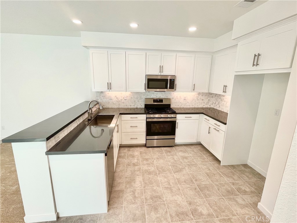 39396 Corvina Lane Temecula, CA 92591 - Photo 9 of 63 a kitchen with white cabinets sink and stainless steel appliances