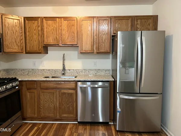 a kitchen with stainless steel appliances granite countertop a refrigerator a stove and a sink with wooden floor