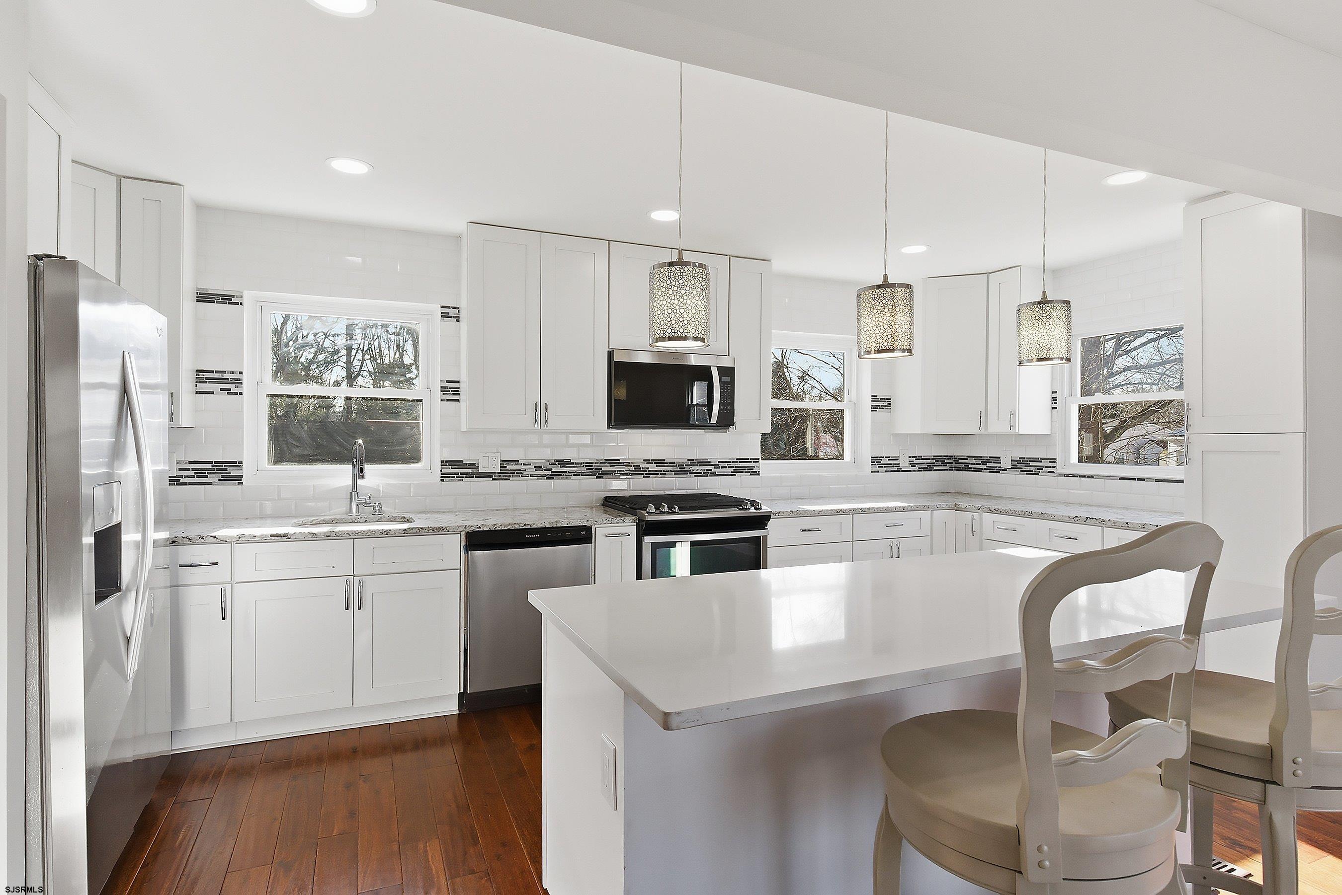 183 Jordan Road Somers Point, NJ 08244 - Photo 14 of 42 a kitchen with stainless steel appliances granite countertop a stove a sink a refrigerator and a dining table with wooden floor