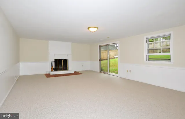 a view of an empty room with a window and a kitchen