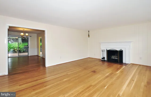 a view of empty room with wooden floor and a fireplace