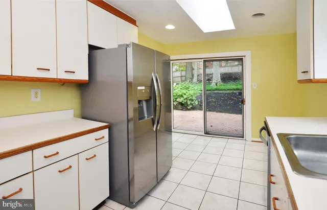 a kitchen with white cabinets a refrigerator and a sink