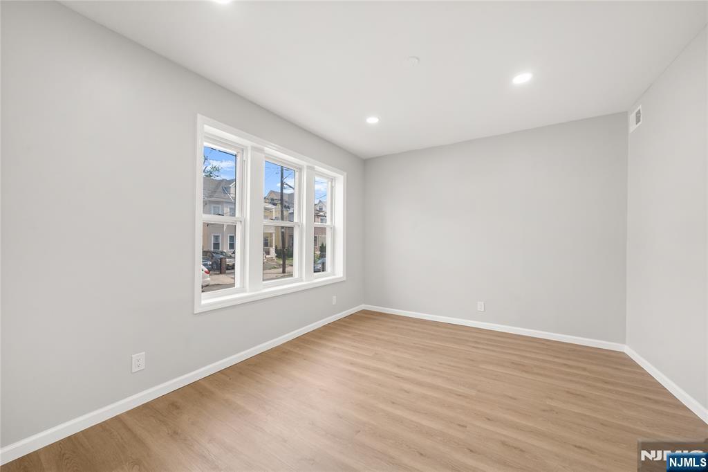53 Henry Street, Unit D1 Passaic, NJ 07055 - Photo 11 of 16 an empty room with wooden floor and windows