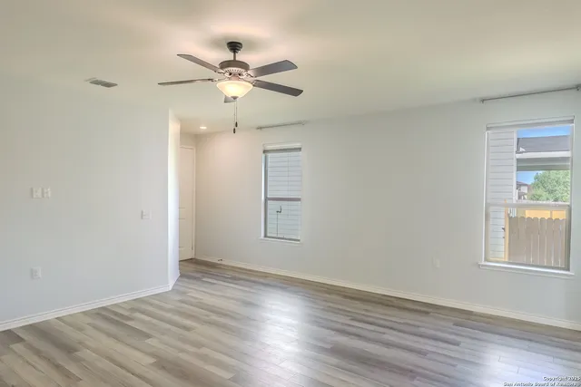 a view of an empty room with wooden floor and a window