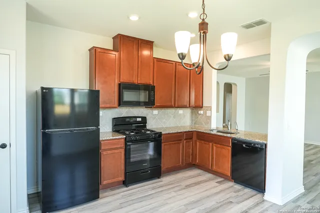 a kitchen with stainless steel appliances granite countertop a refrigerator a stove and a sink