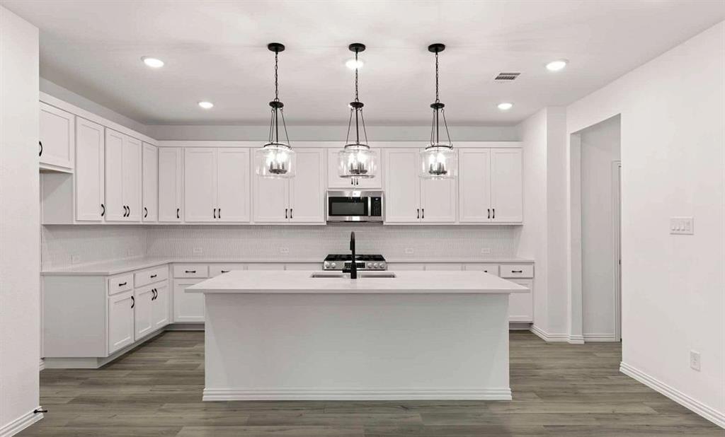 14204 Gallatin Street Pilot Point, TX 76258 - Photo 7 of 14 a view of a kitchen with kitchen island white cabinets and stainless steel appliances