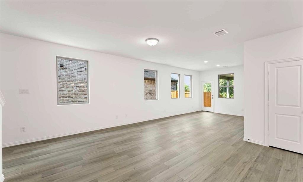 14204 Gallatin Street Pilot Point, TX 76258 - Photo 8 of 14 an empty room with wooden floor and windows