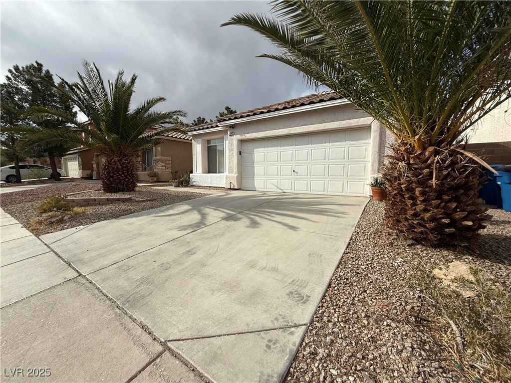 7062 Russell Ranch Avenue Las Vegas, NV 89113 - Photo 2 of 32 Ranch-style home with a tile roof, concrete driveway, a garage, and stucco siding