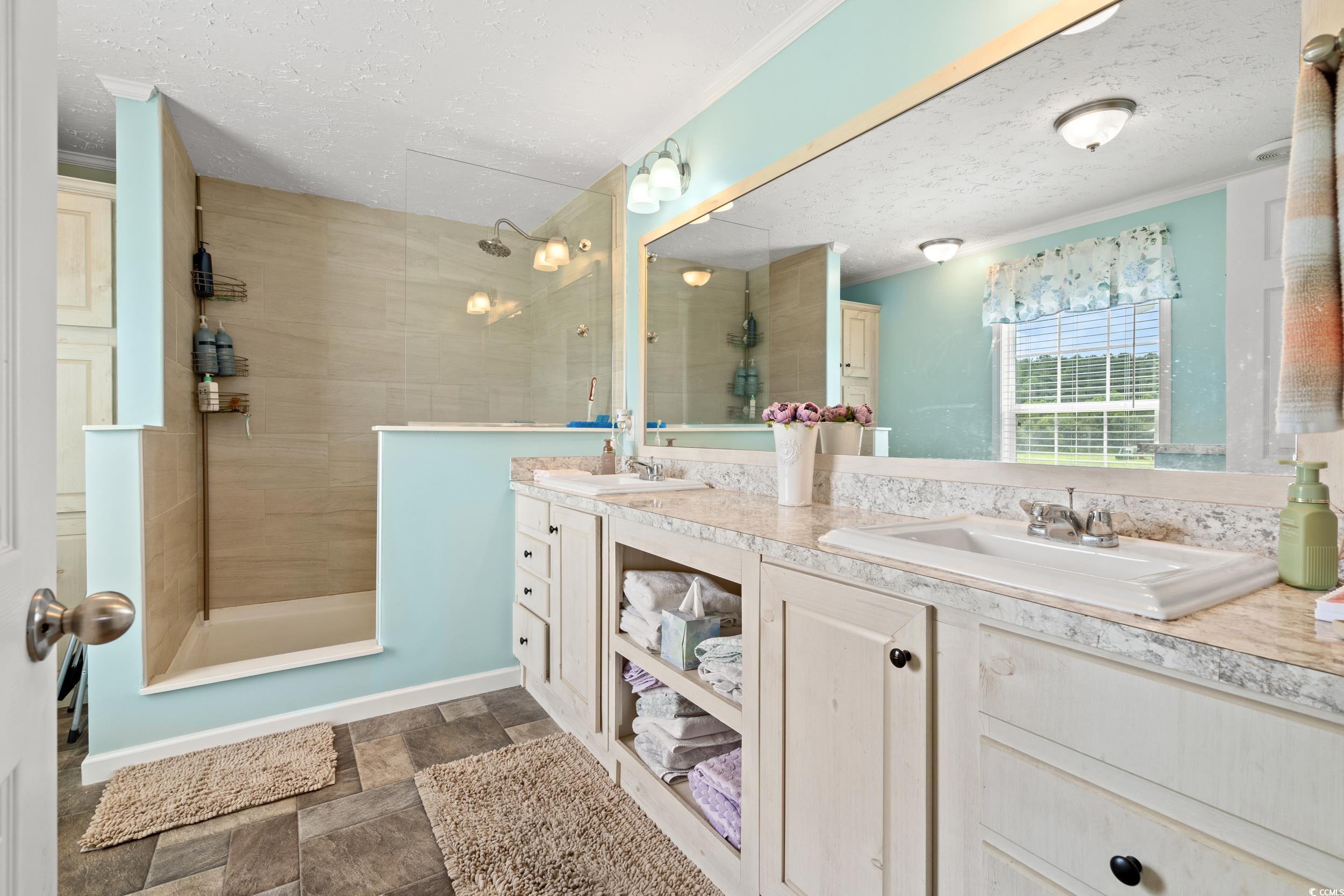 399 Calico Road Loris, SC 29569 - Photo 17 of 30 Full bathroom with walk in shower, double vanity, a textured ceiling, stone finish flooring, and ornamental molding
