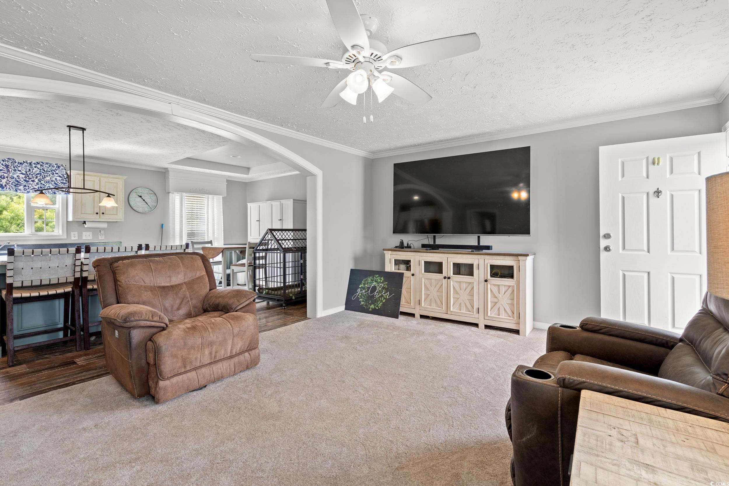 399 Calico Road Loris, SC 29569 - Photo 4 of 30 Carpeted living area featuring a textured ceiling, ornamental molding, a ceiling fan, arched walkways, and a chandelier