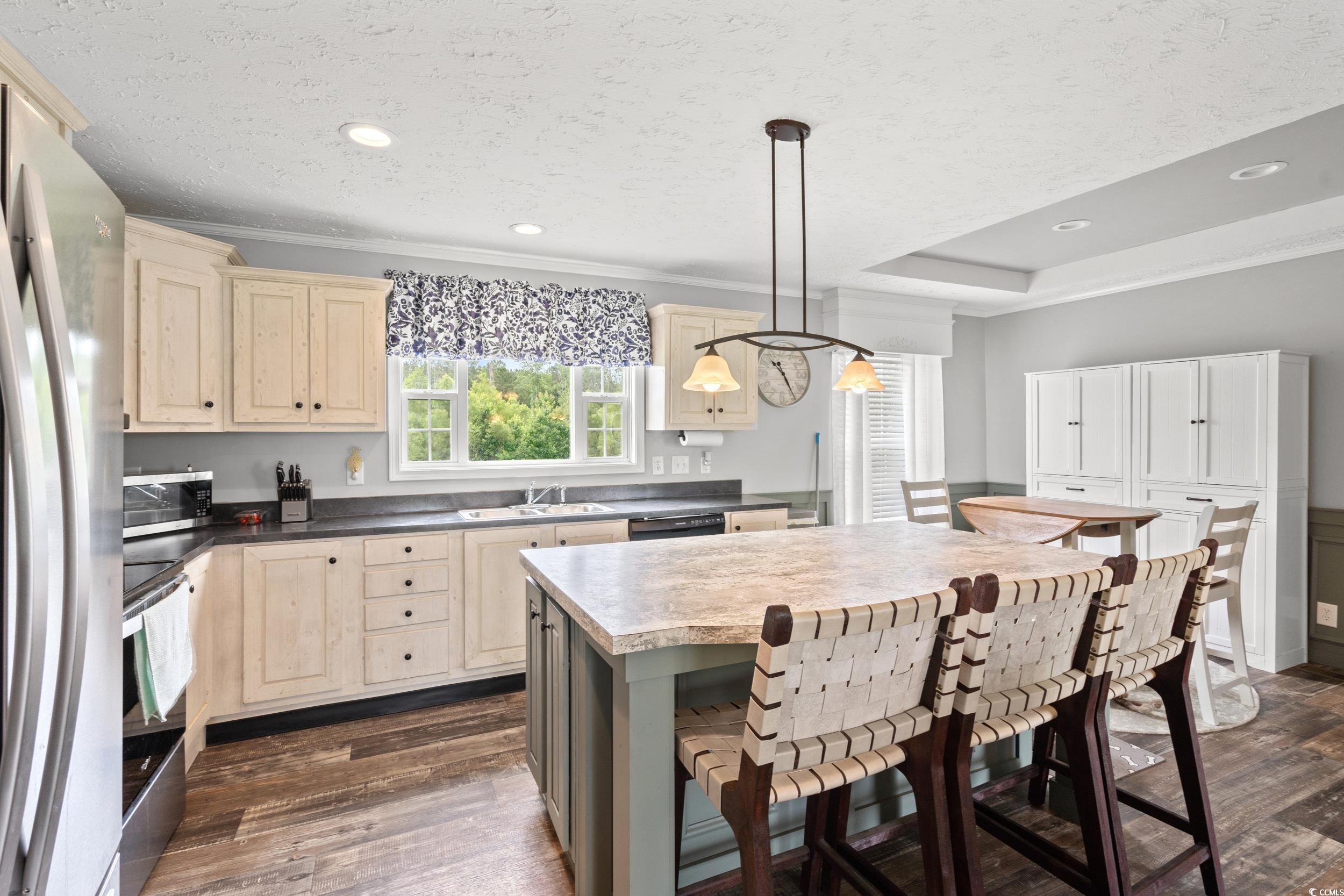 399 Calico Road Loris, SC 29569 - Photo 8 of 30 Kitchen with stainless steel appliances, cream cabinetry, dark wood-style flooring, a textured ceiling, and ornamental molding