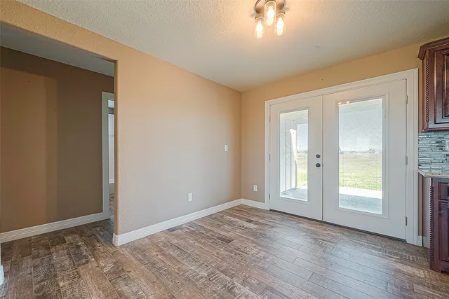a view of an empty room with wooden floor and window