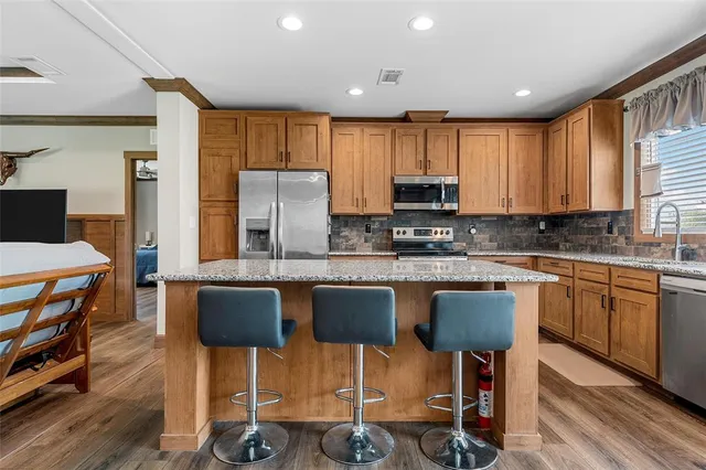 a kitchen with granite countertop a table chairs stove a sink dishwasher and cabinets with wooden floor